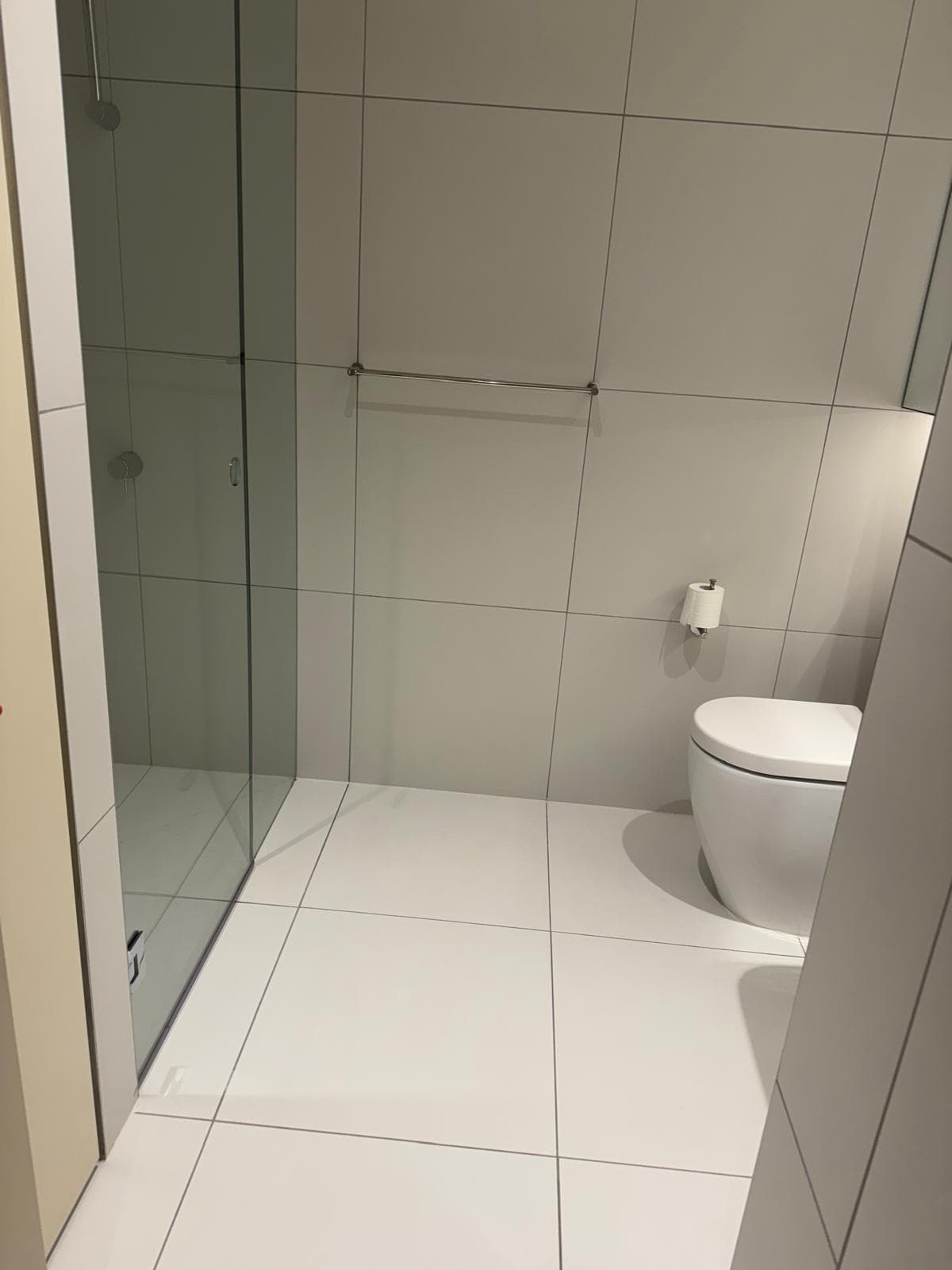 Bathroom after bond cleaning — tiles, fixtures and glass shower screen